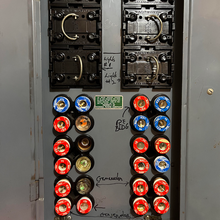 Wadsworth screw-in fuse panel with handwritten circuit labels and red and blue fuses in a residential panel box